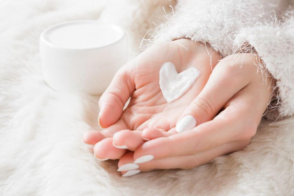 Women's hands with cream in shape of a heart